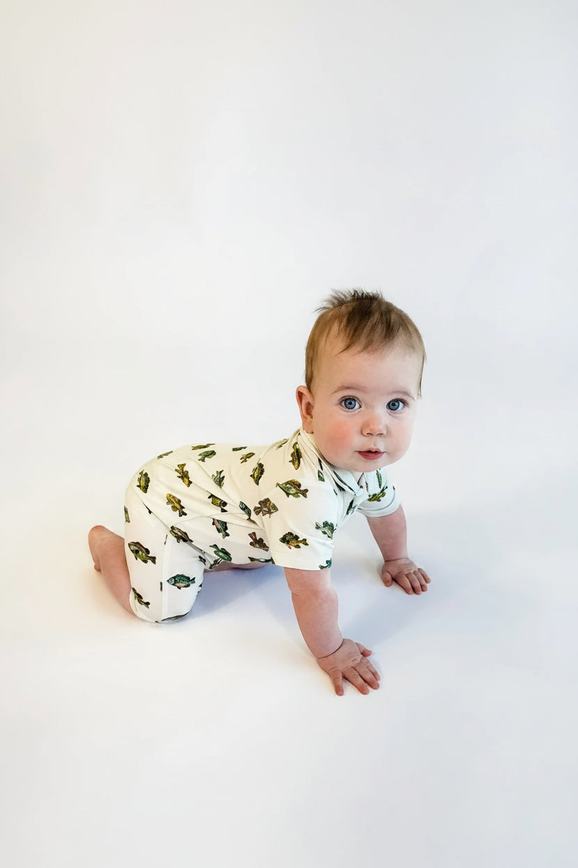Baby wearing a white onesie with green patterns on a white background