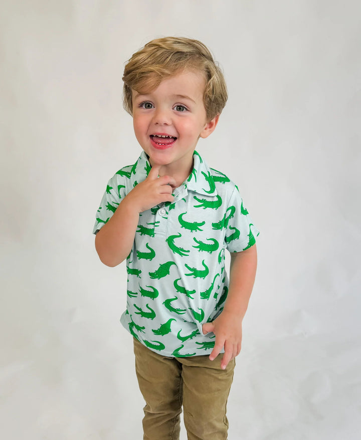 Child wearing a green shirt with dinosaur pattern on a plain background