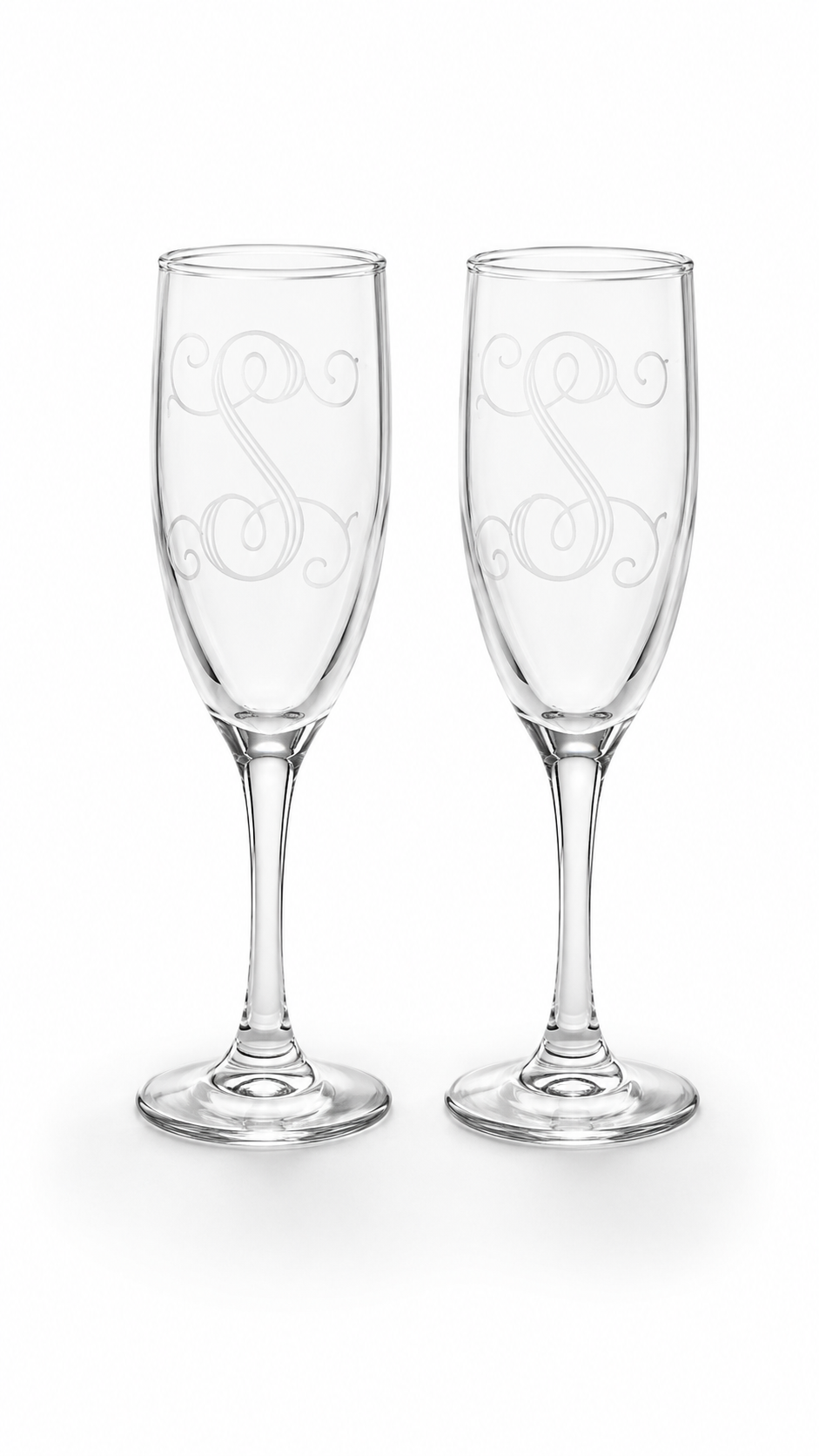 Two clear champagne flutes with elegant etched scrollwork monogram designs, shown side-by-side on a white background.