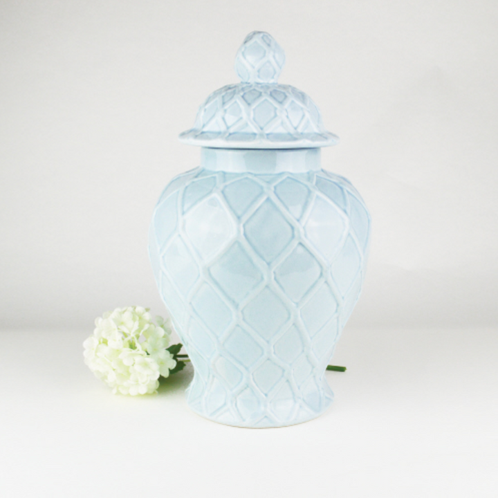 A light blue textured ginger jar with a lid, displayed alongside a white flower.
