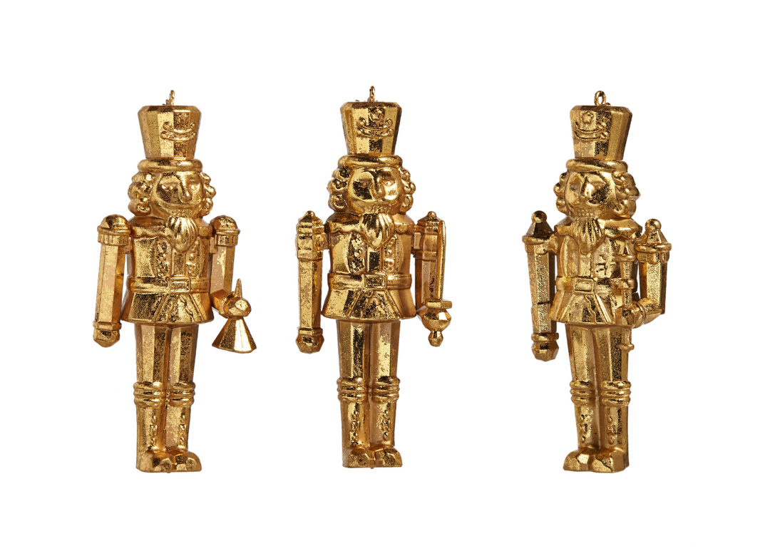 Three gold nutcracker figurines on a white background