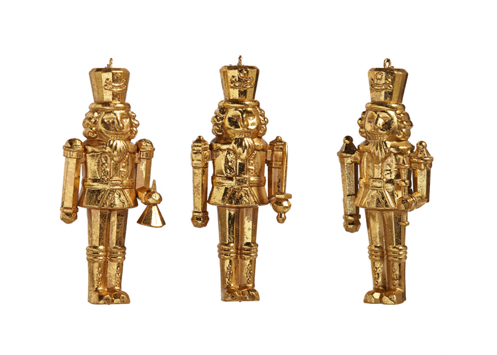 Three gold nutcracker figurines on a white background