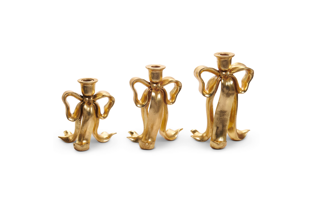 Three gold angel-shaped candle holders on a white background