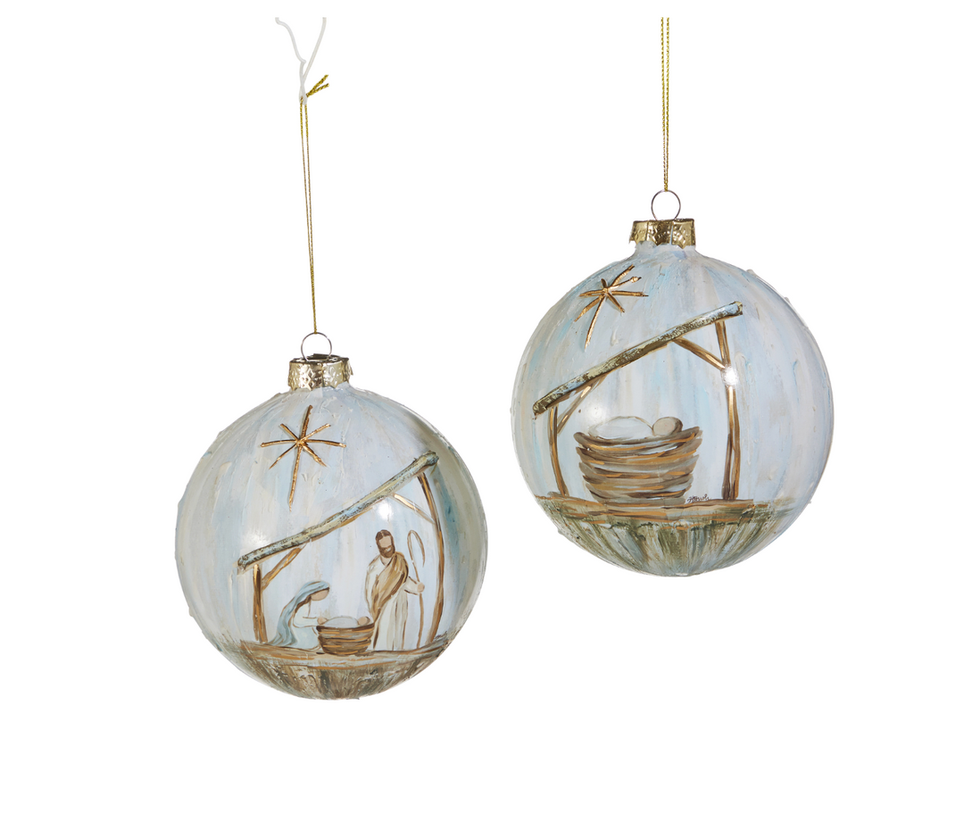 Two glass Christmas ornaments with nativity scene designs on a white background