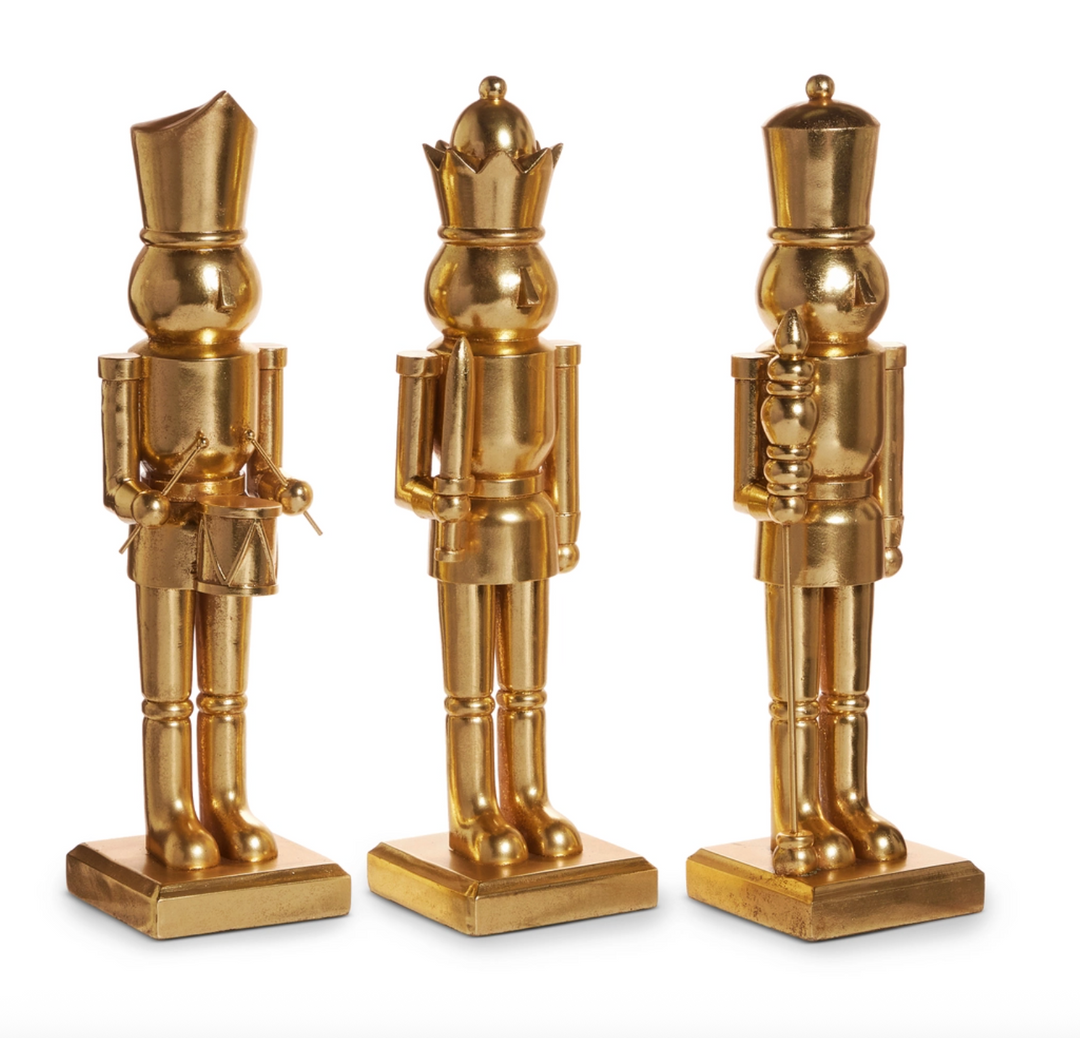 Three gold nutcracker figurines on a white background