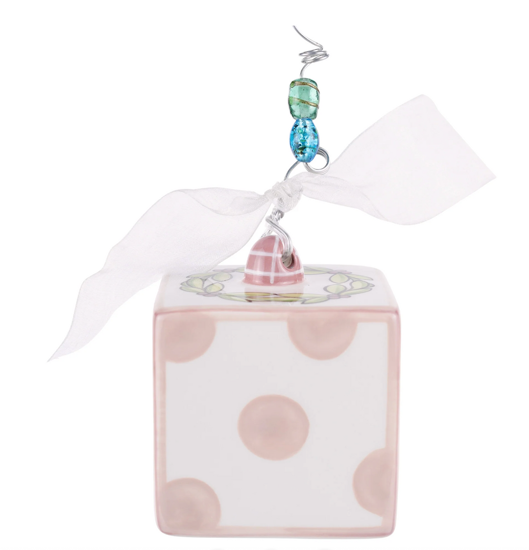 Decorative cube with polka dots and a blue bead on a white background