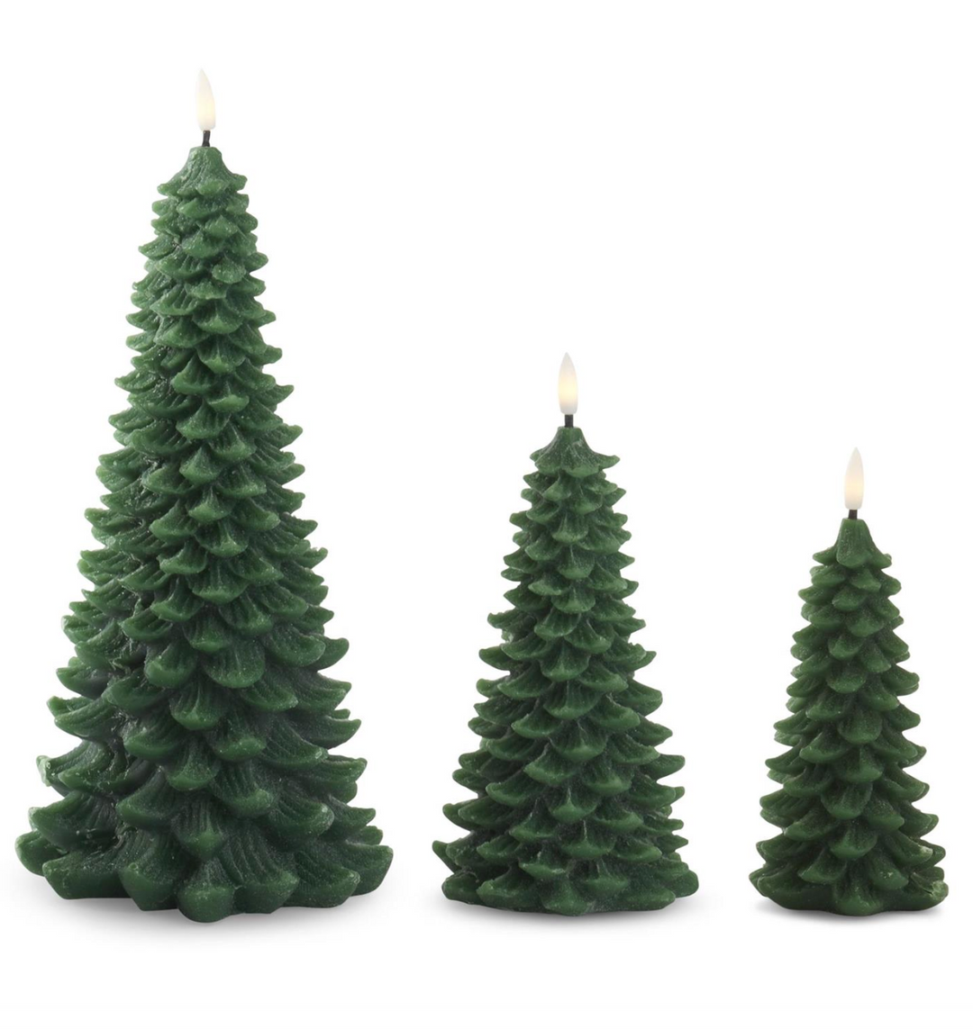 Three green tree-shaped candles on a white background