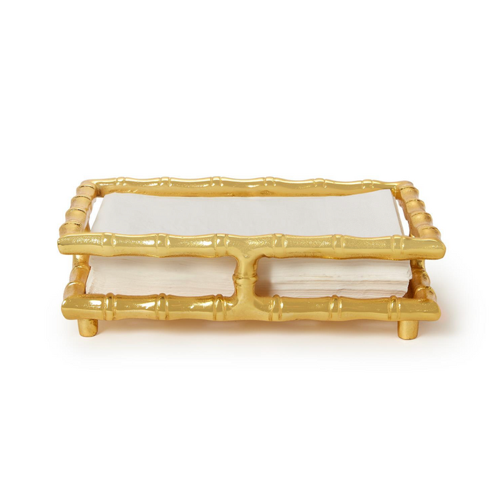 Gold bamboo-style napkin holder with white napkins on a white background