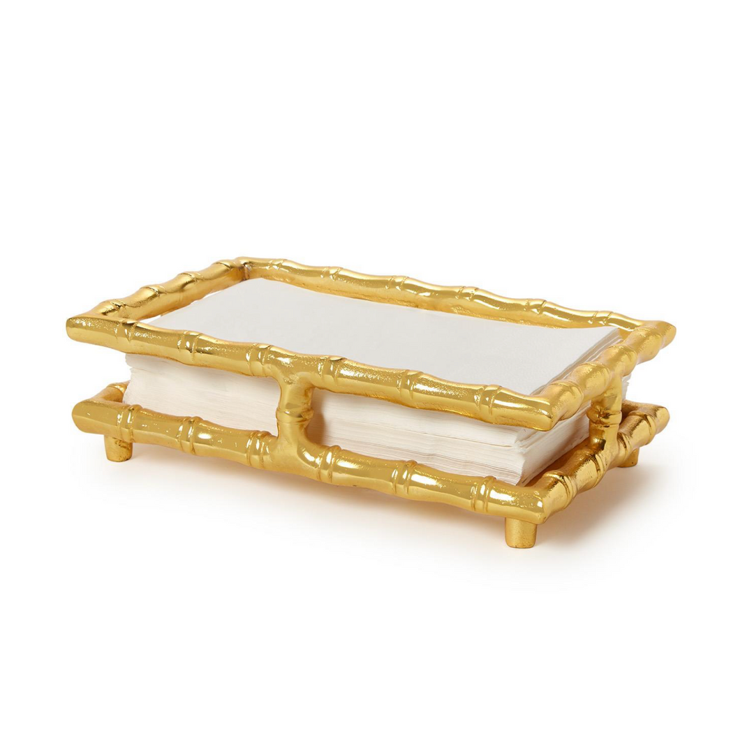 Gold bamboo-style napkin holder with white napkins on a white background