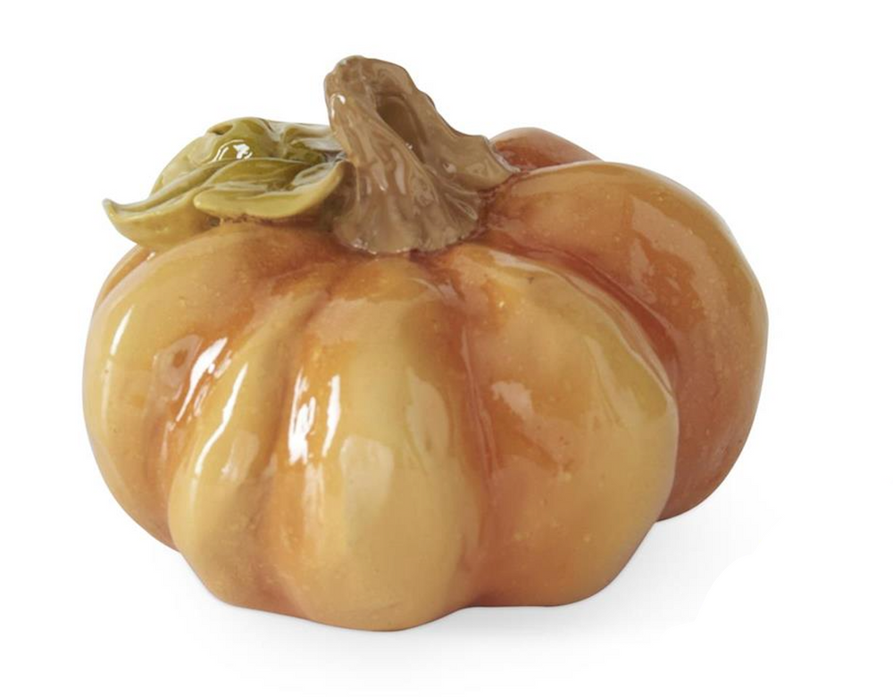 A glossy ceramic decorative pumpkin figurine in warm orange and yellow tones with a brown stem and small green leaves, shown on a white background.