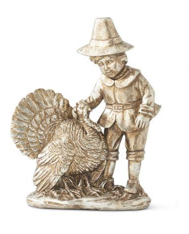 A small decorative figurine of a Native American-style child standing beside a turkey, shown on a plain white background. The figurine has a weathered metallic or stone-like finish in warm beige and gray tones.