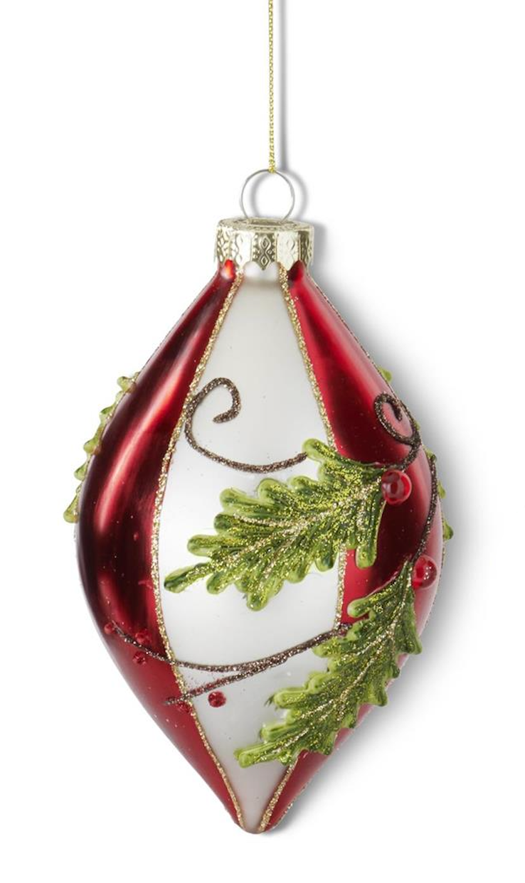 A red and white Christmas ornament with green pine branch details and gold glitter accents, hanging against a white background.