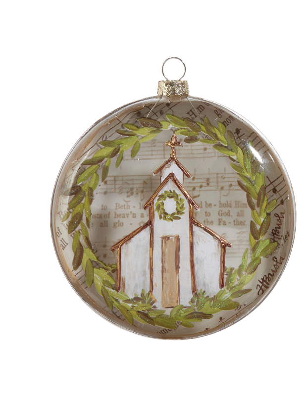 A round clear glass Christmas ornament featuring a painted white church with a green wreath, surrounded by a green laurel wreath and scriptural text background.