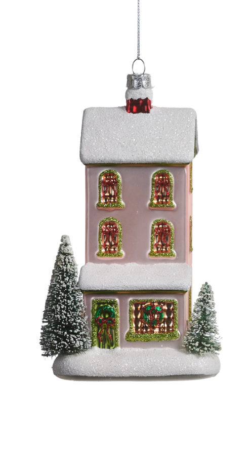 A pink Christmas house ornament with a snowy white roof and base, decorated with red and green window details, small frosted Christmas trees, and a silver hanging cap on a white background.