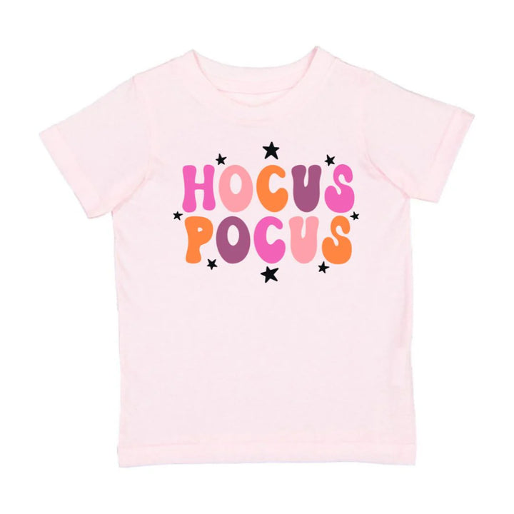 Pink t-shirt with 'HOCUS POCUS' text in colorful letters on a white background