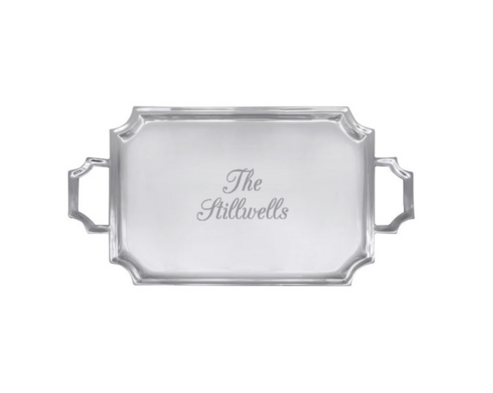 A rectangular silver serving tray with decorative corner details and two side handles, featuring the personalized name 'The Stillwells' engraved in the center, shown on a plain white background.