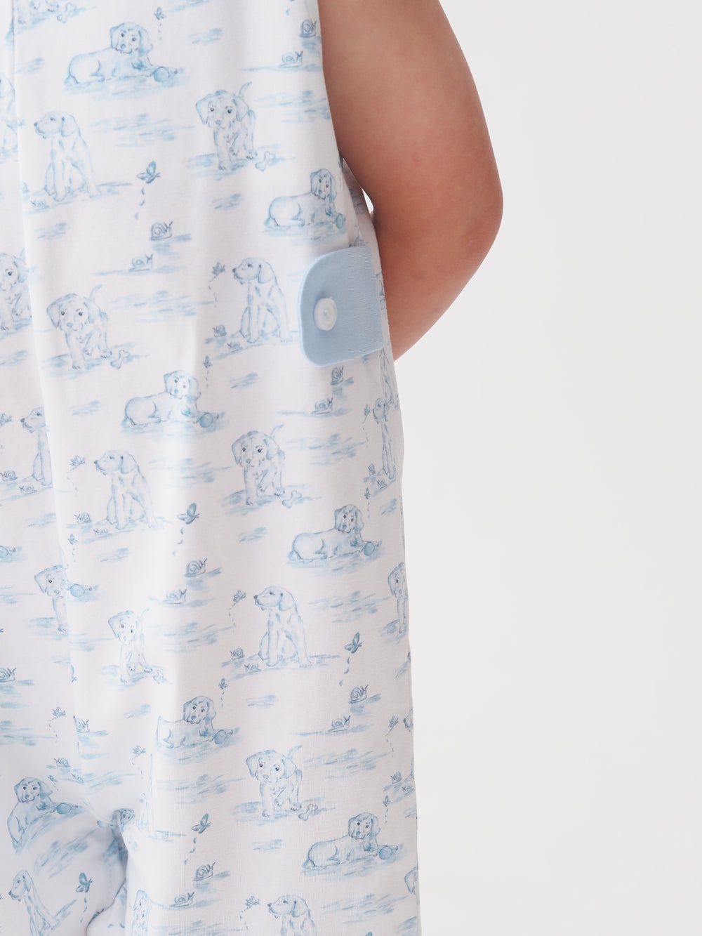 Close-up of a white garment with blue puppy pattern and button detail.