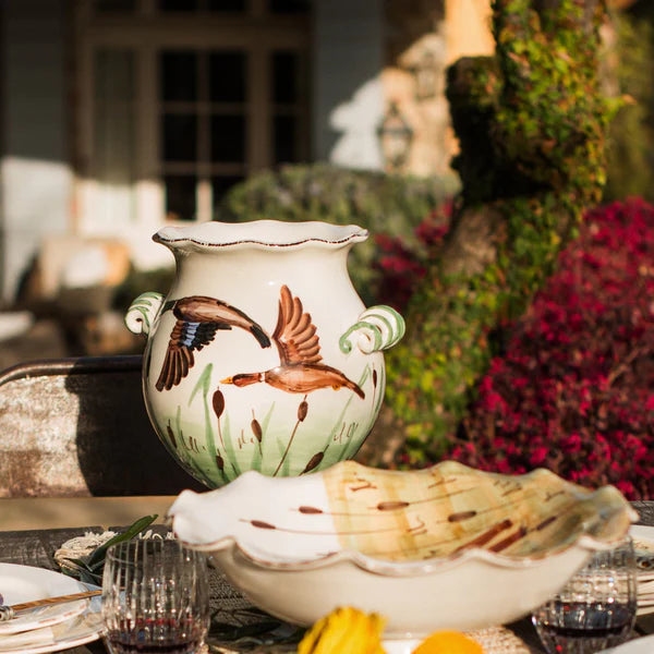 Decorative ceramic vase with bird design on a table outdoors.