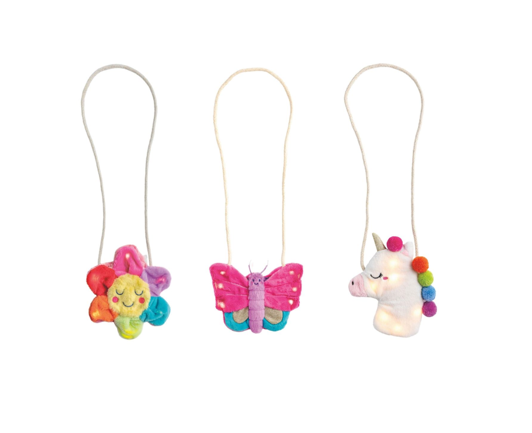 Three colorful plush purses on strings, including a unicorn, butterfly, and rainbow-colored character, on a white background.