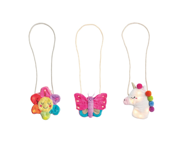 Three colorful plush purses on strings, including a unicorn, butterfly, and rainbow-colored character, on a white background.