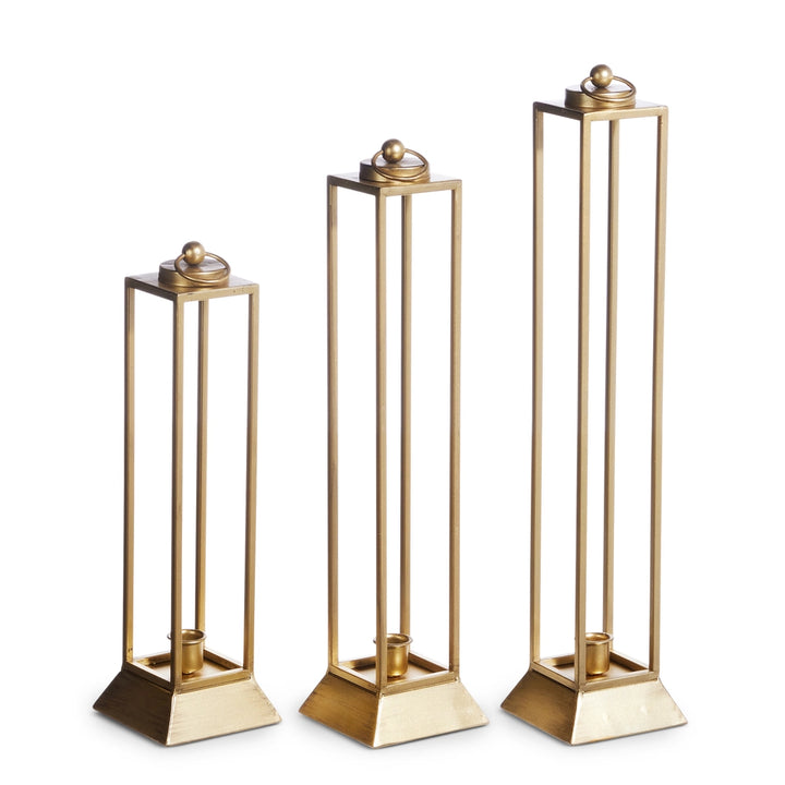 Three gold candle holders of different heights on a white background