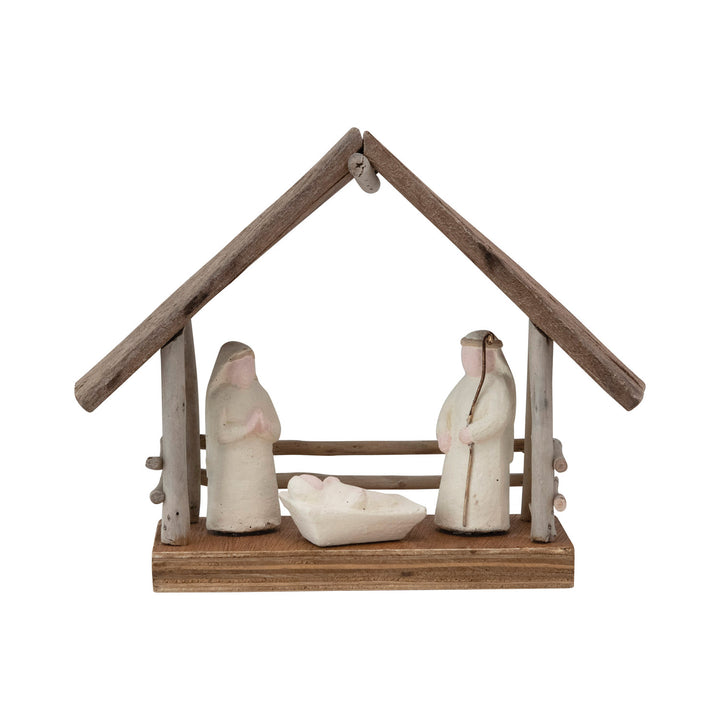 Small nativity scene with three figures and a wooden shelter on a white background