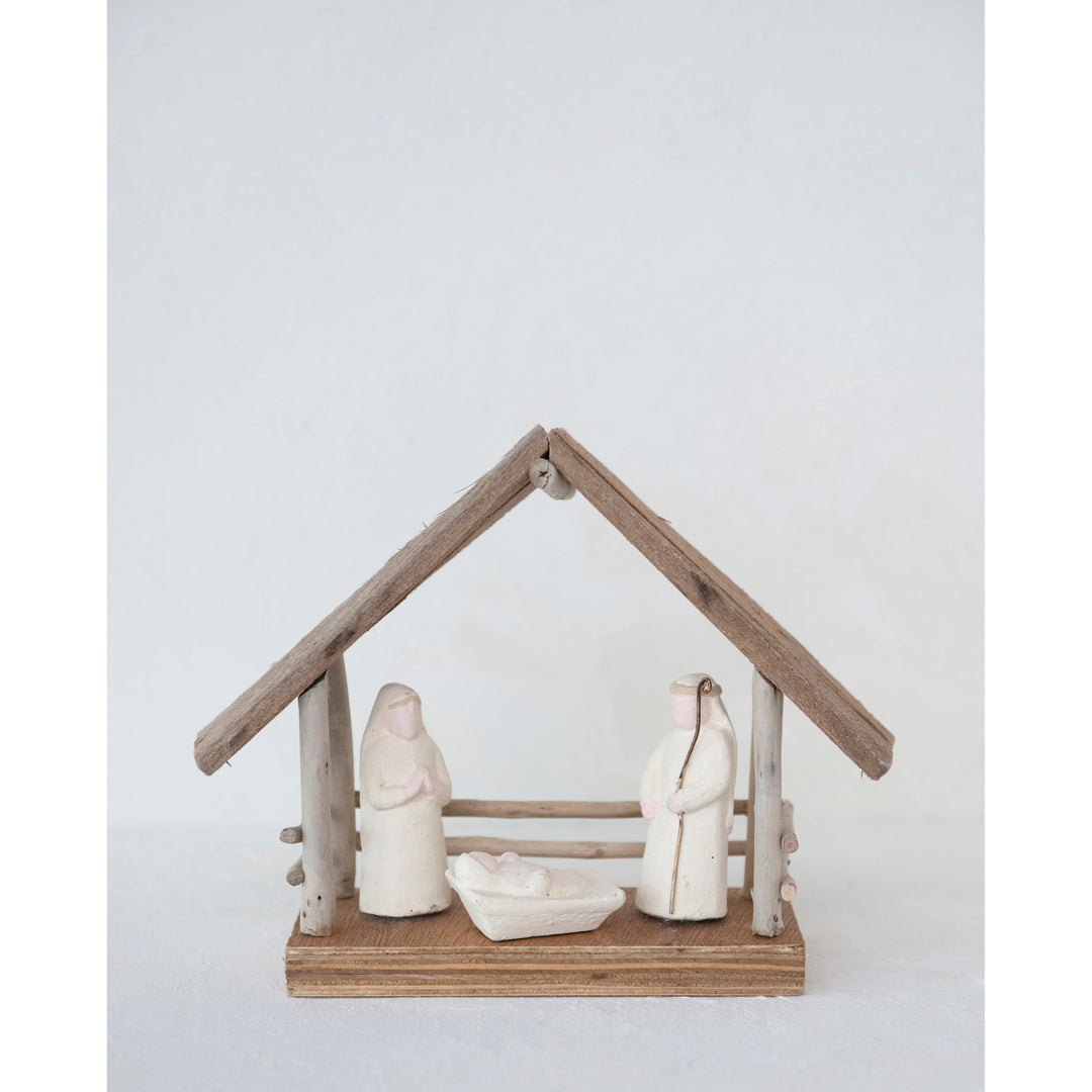 Small nativity scene with wooden stable and figures on a white background