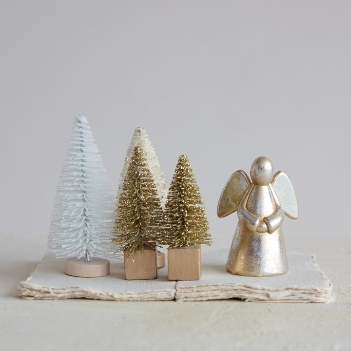 Decorative angel figurine and miniature trees on a light background