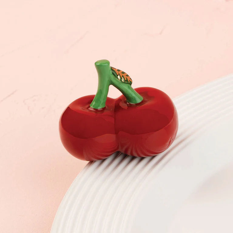 Red pepper-shaped object on a textured surface with a pink background