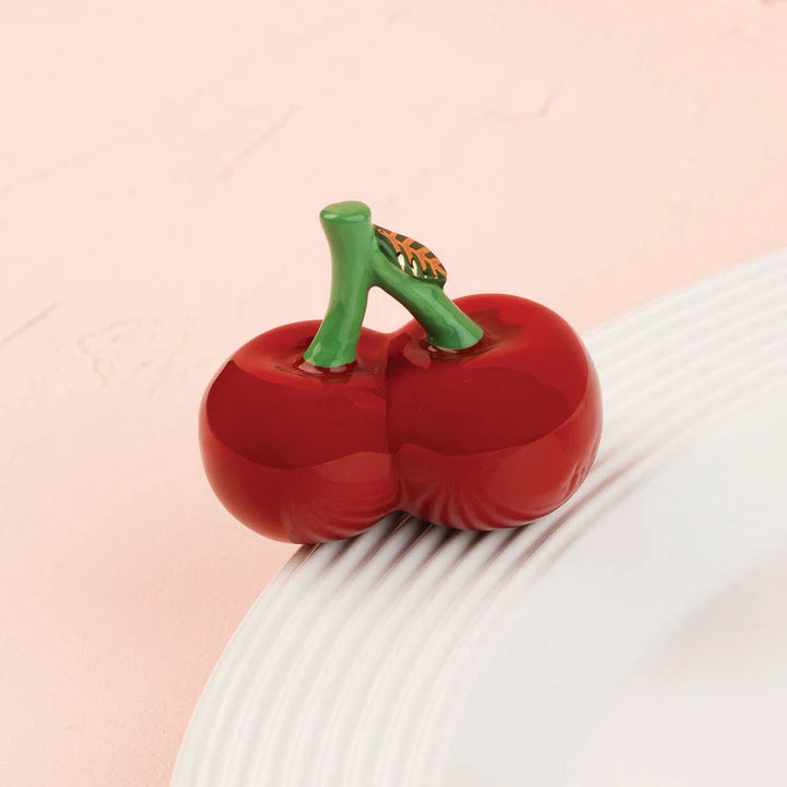 Red pepper-shaped object on a textured surface with a pink background