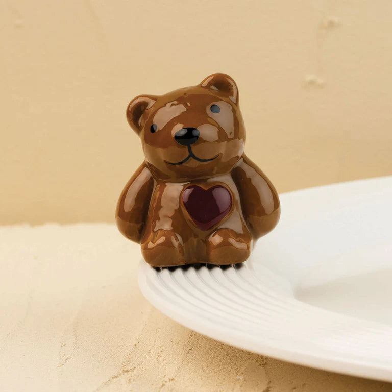 Brown ceramic bear with a red heart on a beige background