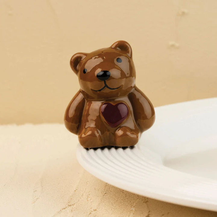 Brown ceramic bear with a red heart on a beige background