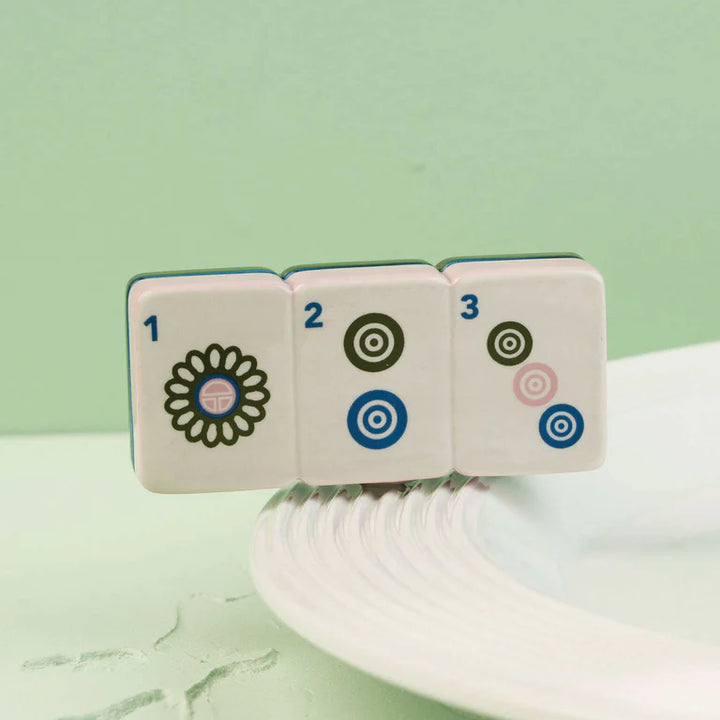 Four game tiles with numbers and symbols on a light green background