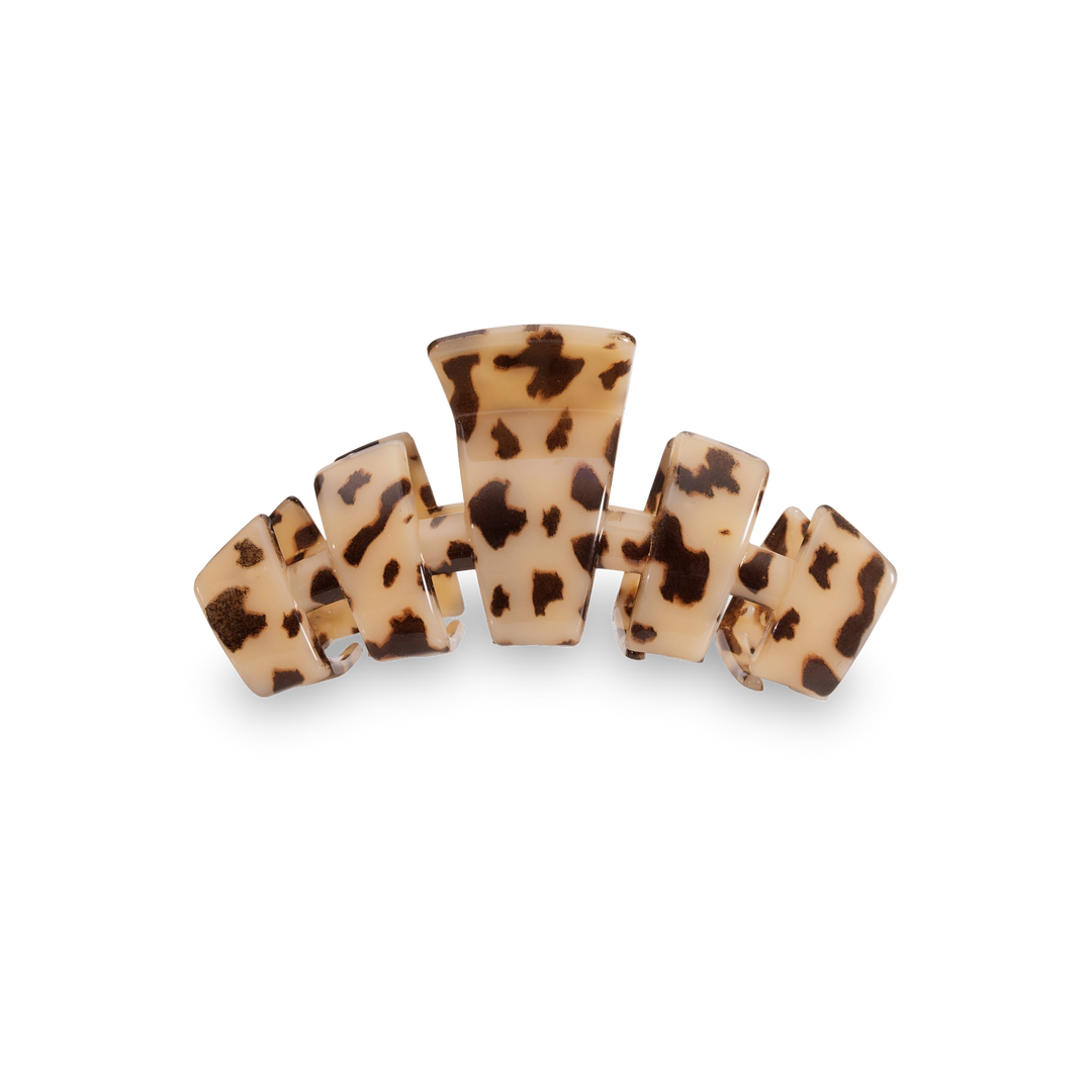 A hair claw clip with a tortoiseshell pattern, featuring a cream-colored base with dark brown and black spots, shown on a plain white background.