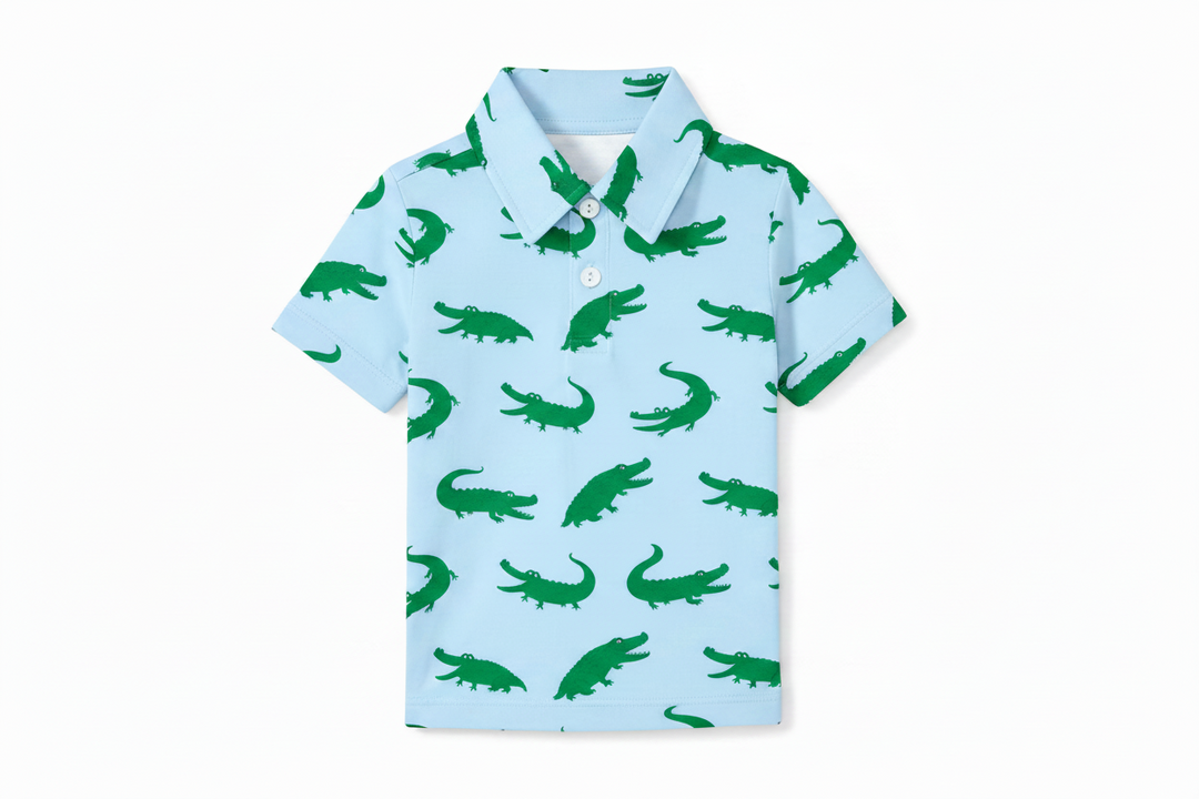 Children's polo shirt with green alligator pattern on a light blue background