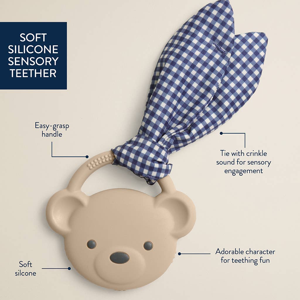 Bear-shaped soft silicone sensory teether with a blue checkered handle on a beige background