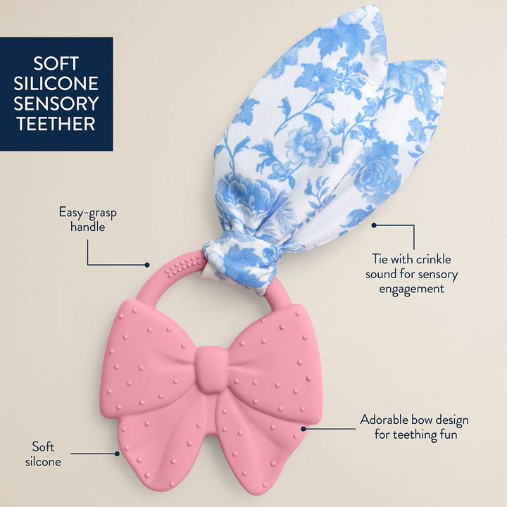 Pink silicone teether with a blue floral headband on a beige background