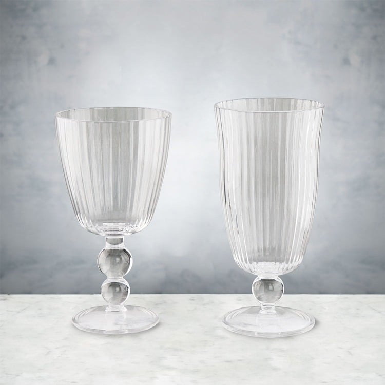 Two clear glass goblets on a marble surface with a gray background
