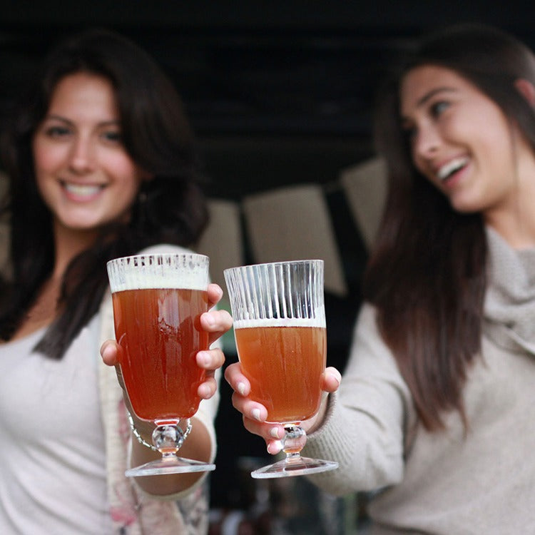 Two women holding glasses of beer in a casual setting