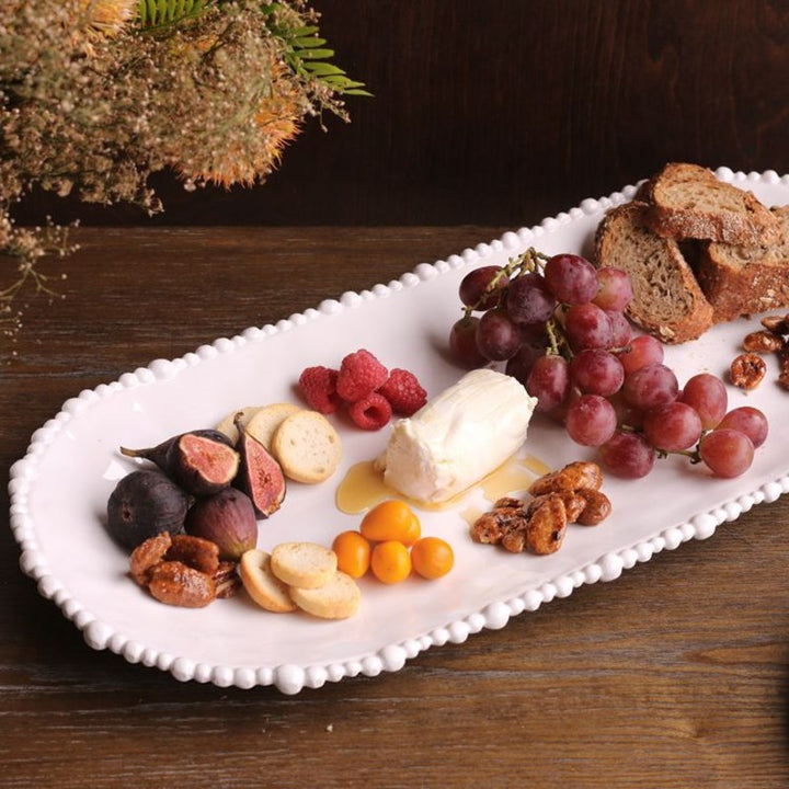 Assorted fruits and nuts on a white platter with a wooden background