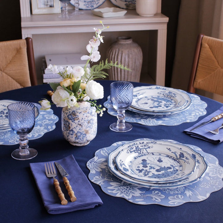 Dining table set with blue and white瓷器, glasses, and floral arrangements.