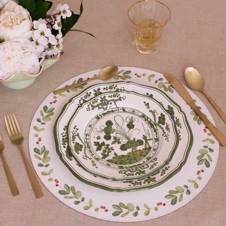Decorative plate with floral design on a table setting with cutlery and flowers.