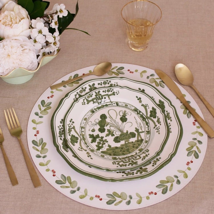 Decorative plate with floral design on a table setting with cutlery and flowers.