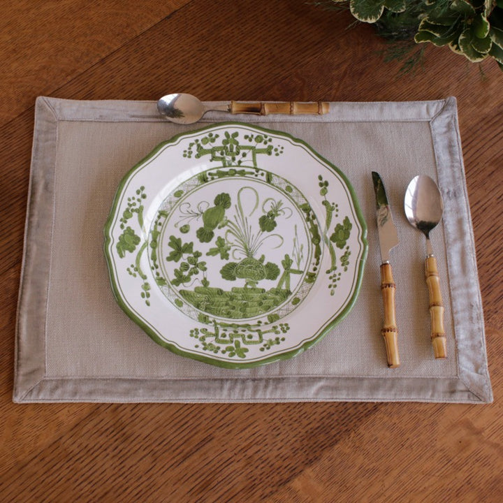 Green and white decorative plate with cutlery on a placemat on a wooden table