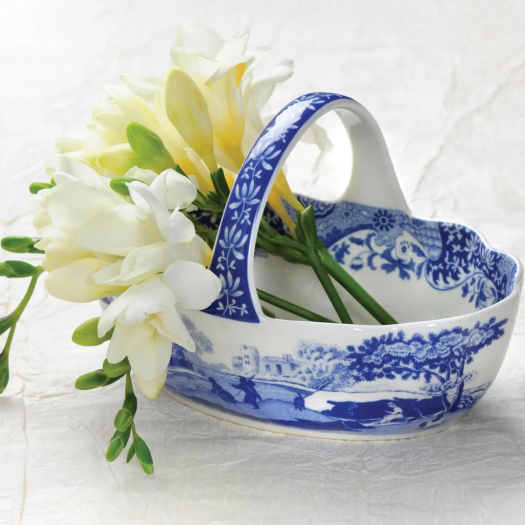 Blue and white ceramic basket with floral design holding flowers on a white background
