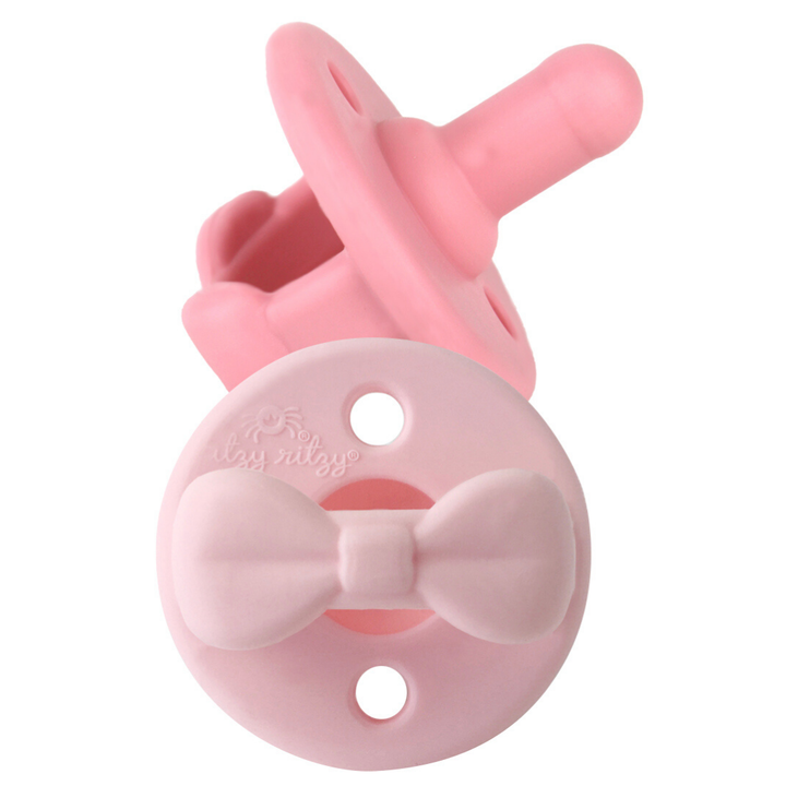 Pink baby pacifier with a bow design on a white background