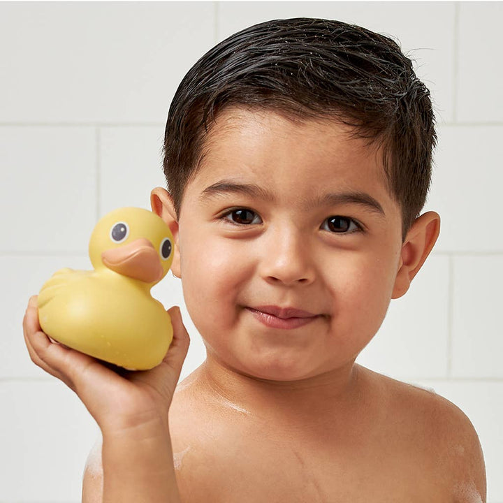 Child holding a yellow rubber duck in a bathroom setting