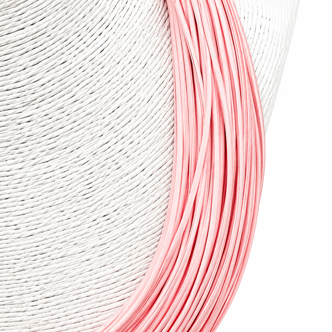 Close-up of pink wire coiled on a textured white surface
