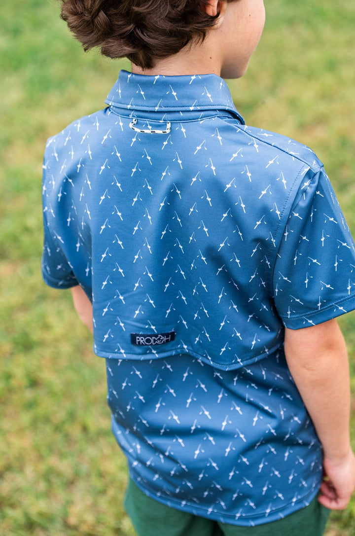 Child wearing a blue shirt with white patterns outdoors