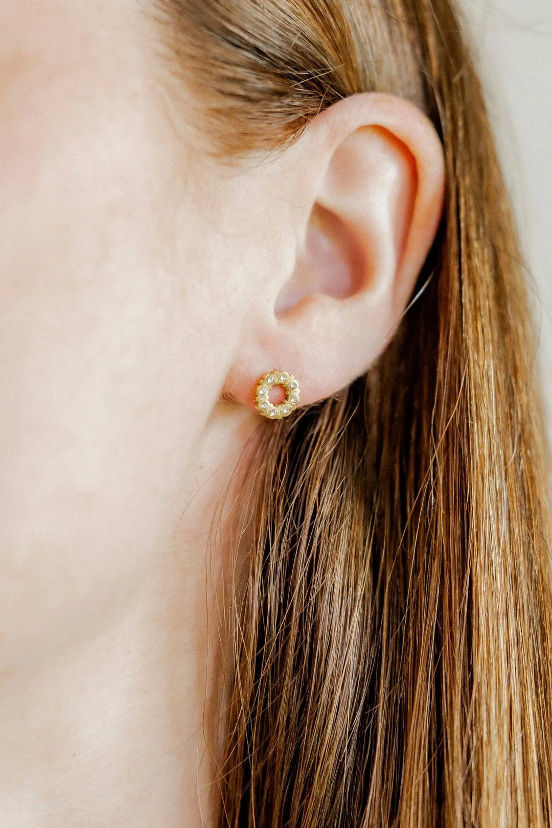 Brinley open-circle CZ gold screwback stud earring worn on the ear
